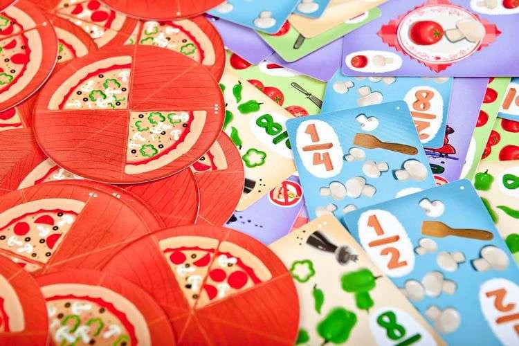 Разложенные игровые карты с пиццами, дробями и ингредиентами.