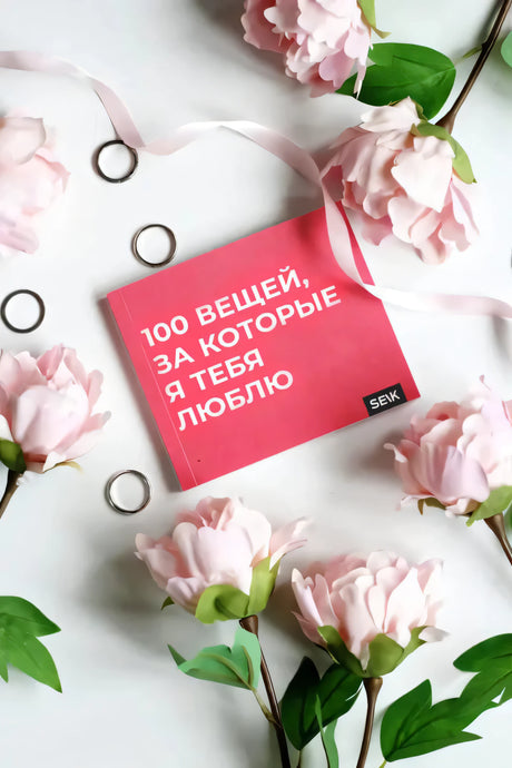 Книга «100 вещей, за которые я тебя люблю» среди розовых цветов
