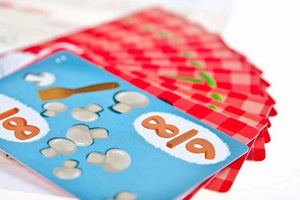 Карты игры с дробями и грибами на фоне красных рубашек.