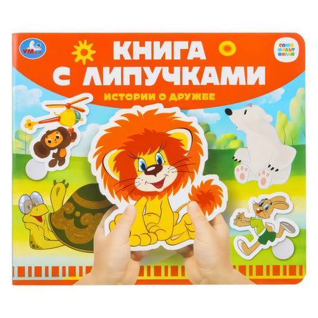 Книга с липучками «Истории о дружбе» издательства Умка — обложка с персонажами Союзмультфильма, руки держат наклейку-льва