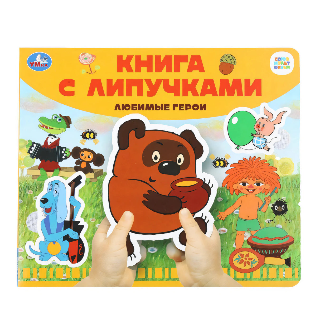 Книга с липучками «Любимые герои» издательства Умка — детские руки держат книгу с персонажами Союзмультфильма