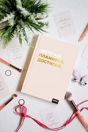 Розовый дневник «Мечтай. Планируй. Достигай.» среди цветов и канцелярии.